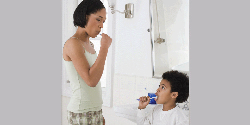 Mother and young son brush their teeth together